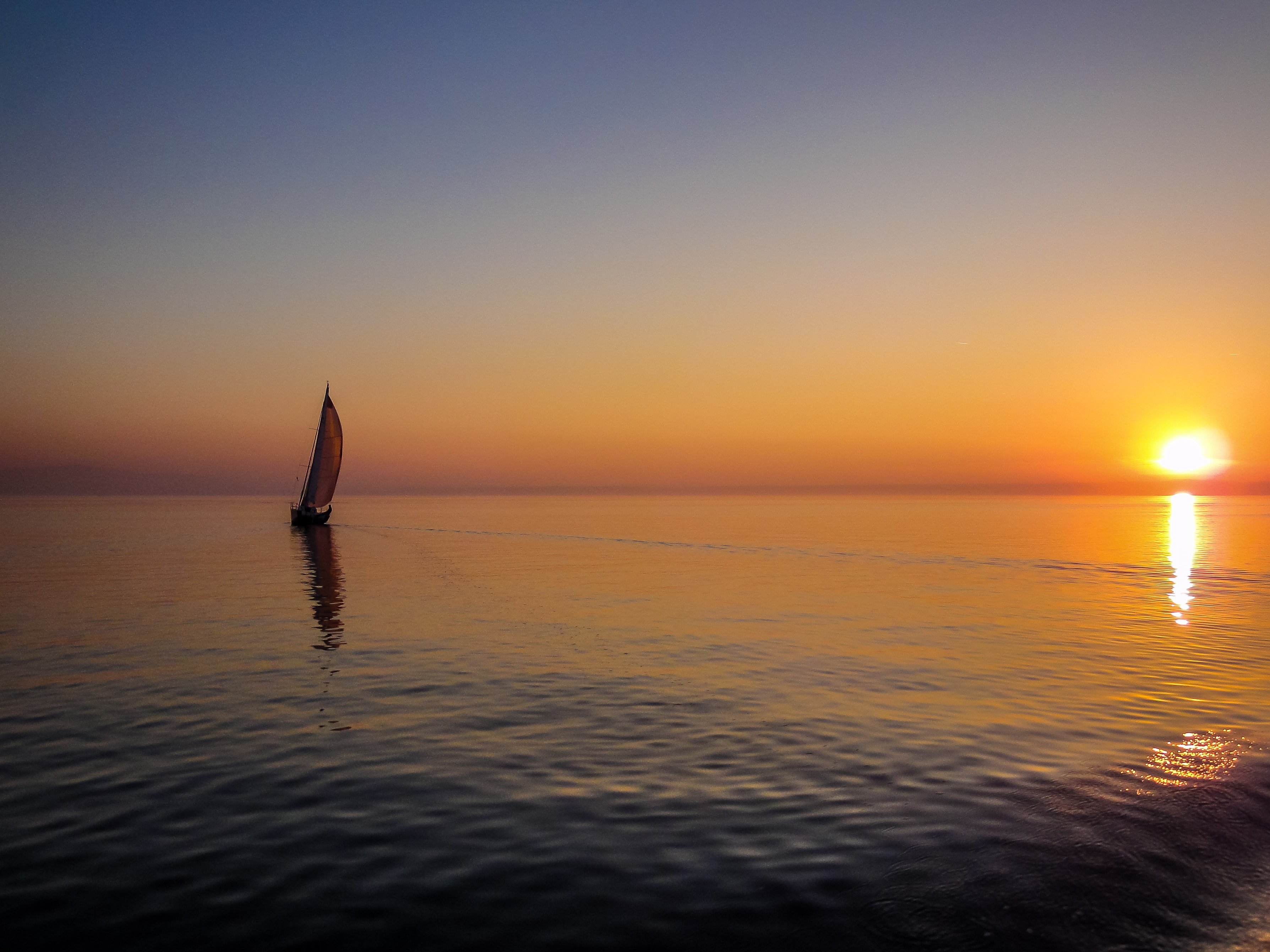 Beautiful image of the sunset over the water with a boat in the distance