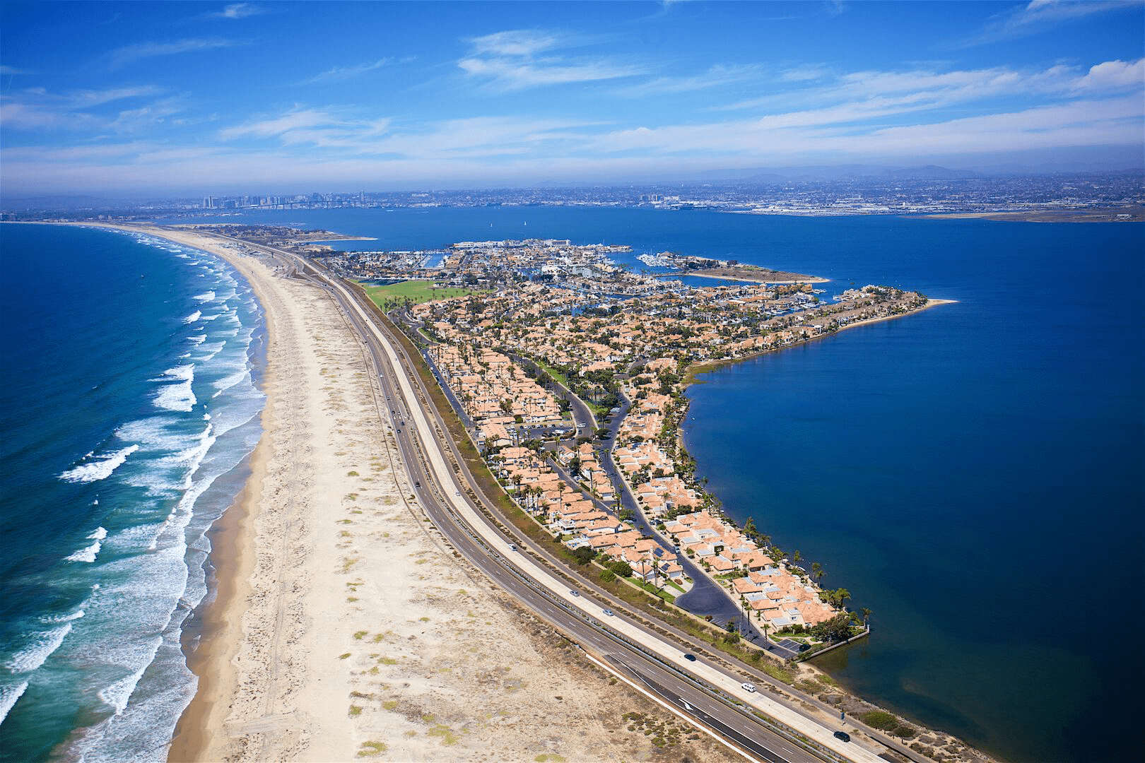 Aerial View of the Coronado Strand with Ocean Waves Hitting the Sandy Beaches and Homes on the Other Side of the Strand