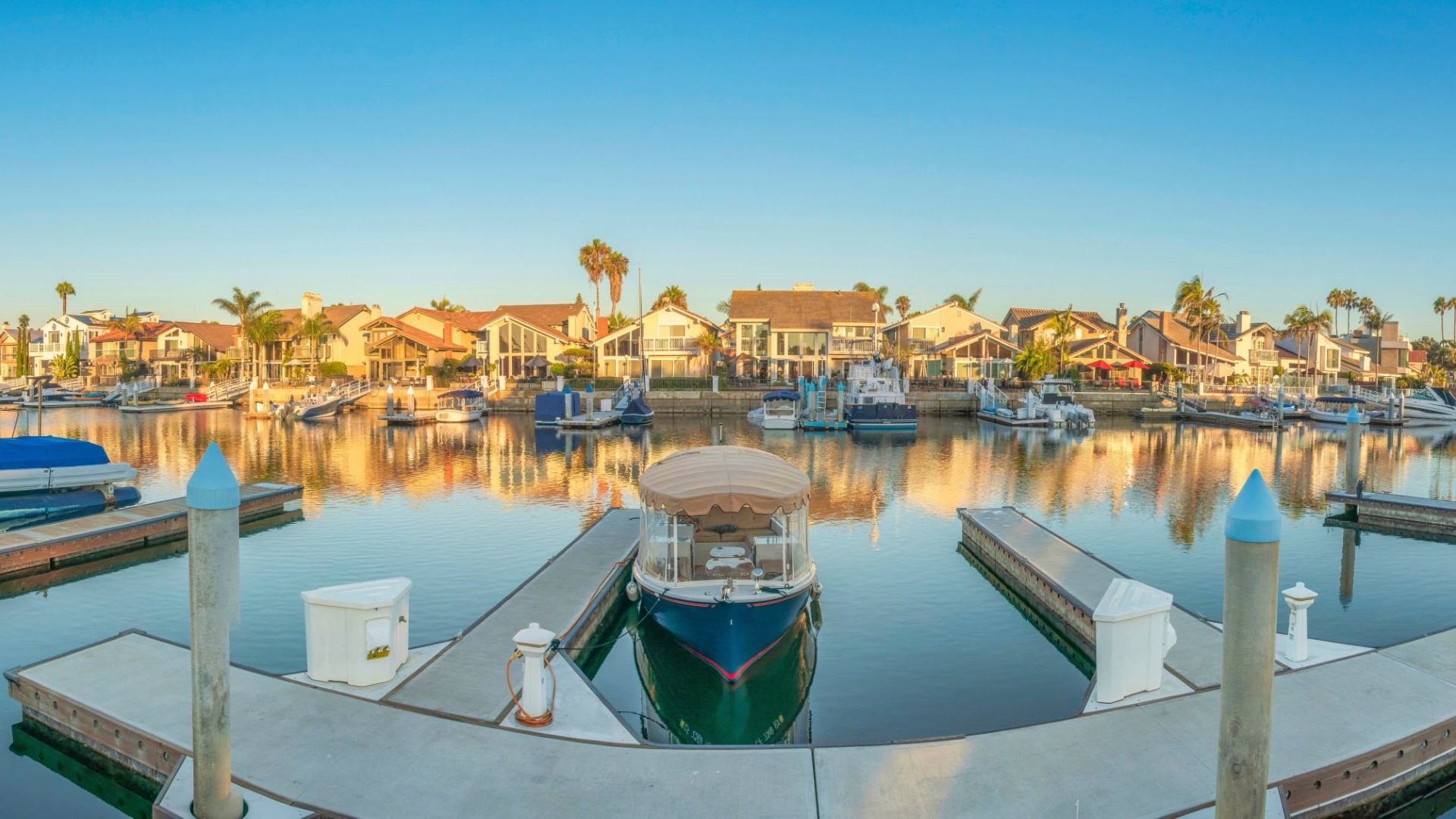 A small boat docked in Coronado Cays with waterfront homes in the background