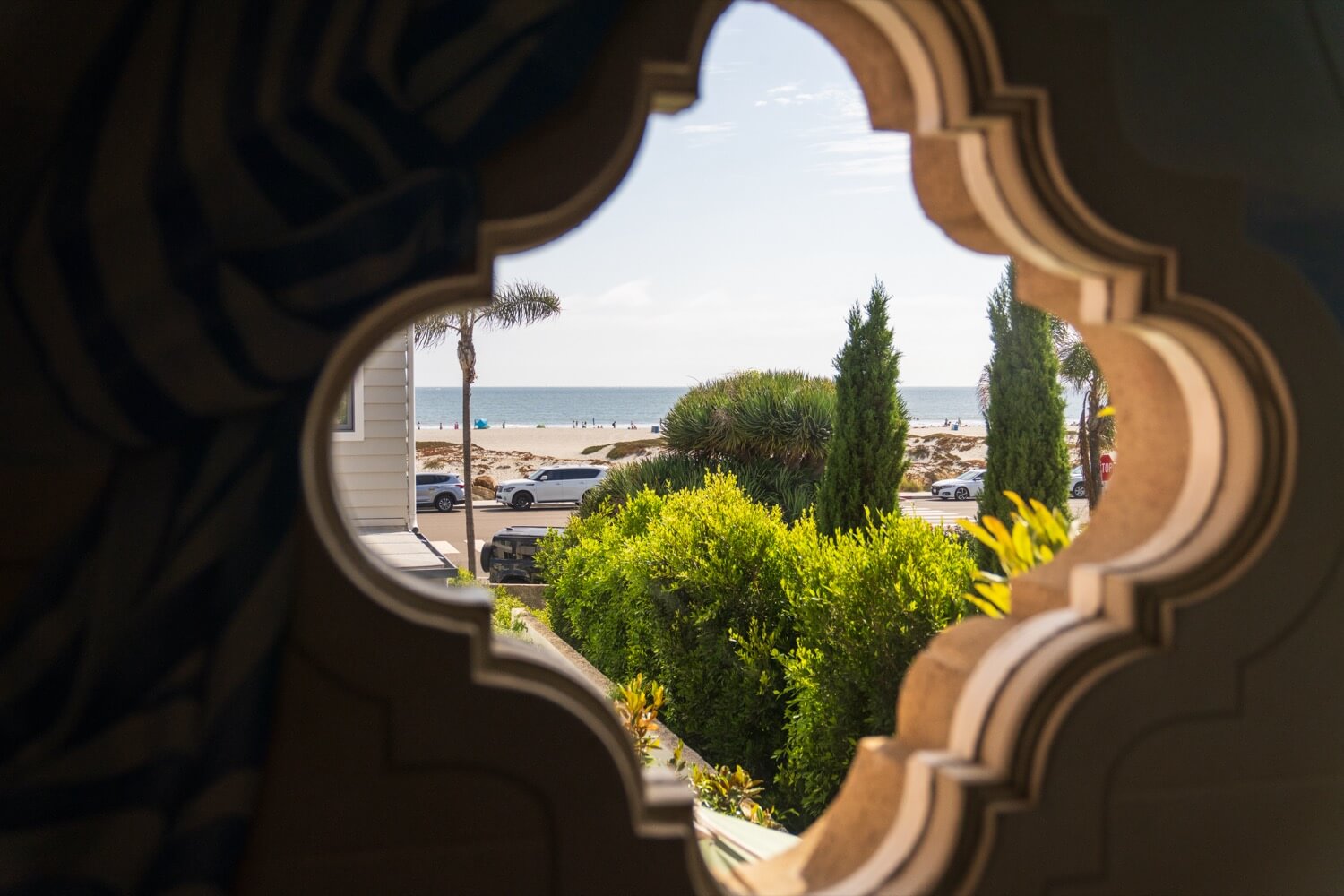 Artistic cross-shaped window frames a view of the Coronado beach, just one block from this luxury home sold by leading Coronado Village realtor Whitney Benzian.