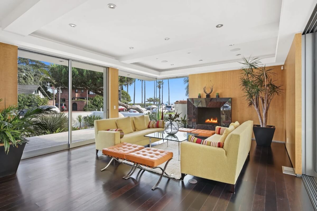 Mid-century inspired living room featuring a wall of windows, a fireplace, and ocean views in a Coronado home.