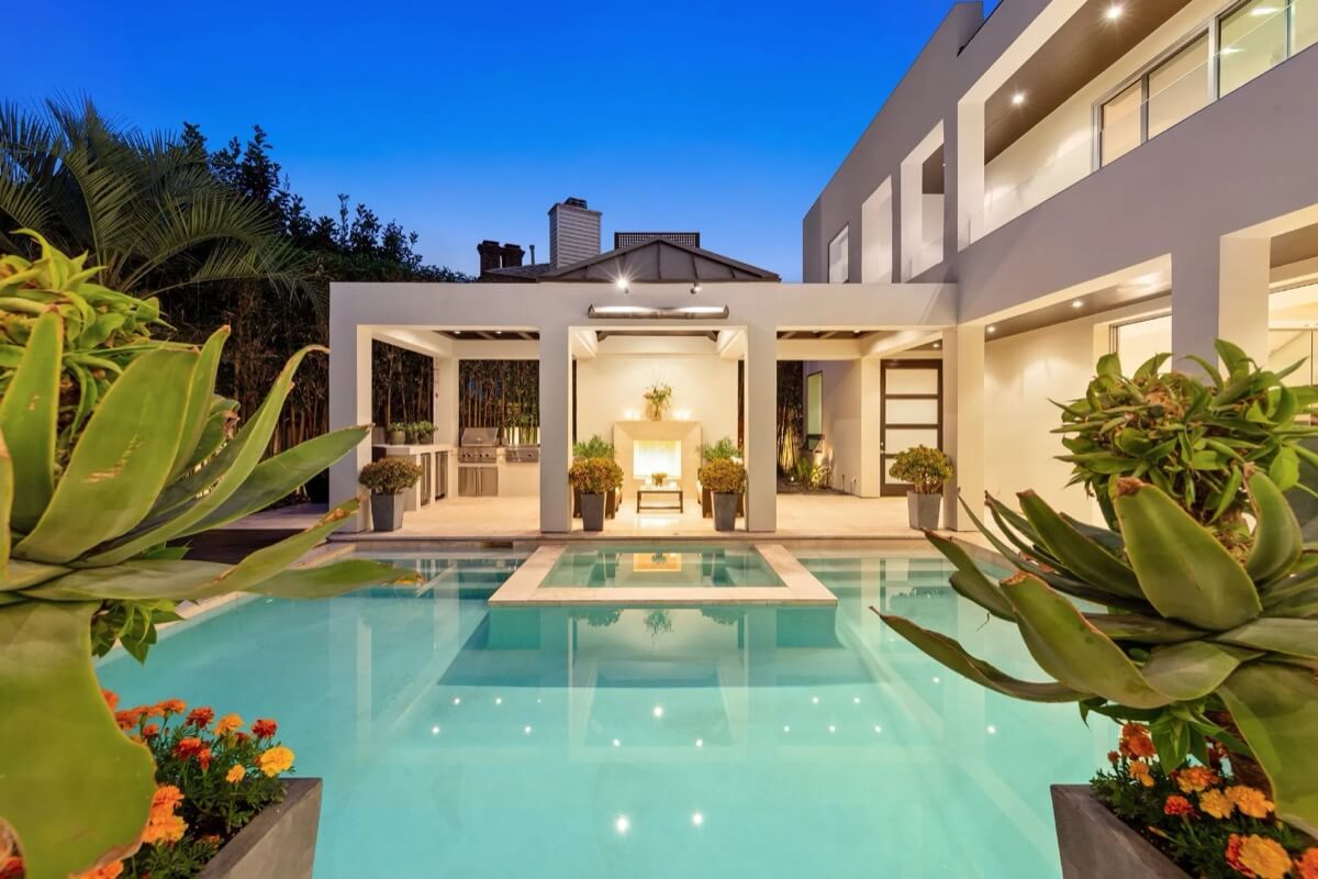 Luxury pool at 1033 Loma Ave illuminated by evening lights, surrounded by an elegant outdoor lounge area.