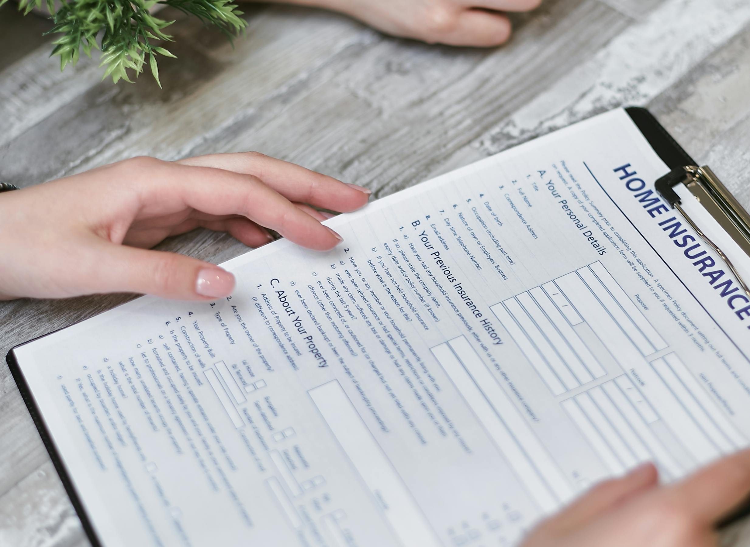 Closeup of person holding home insurance application forms for a Coronado property