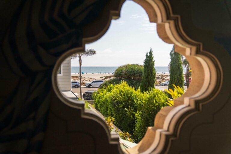 Artistic window in a Coronado beach house looks out to the ocean and sand