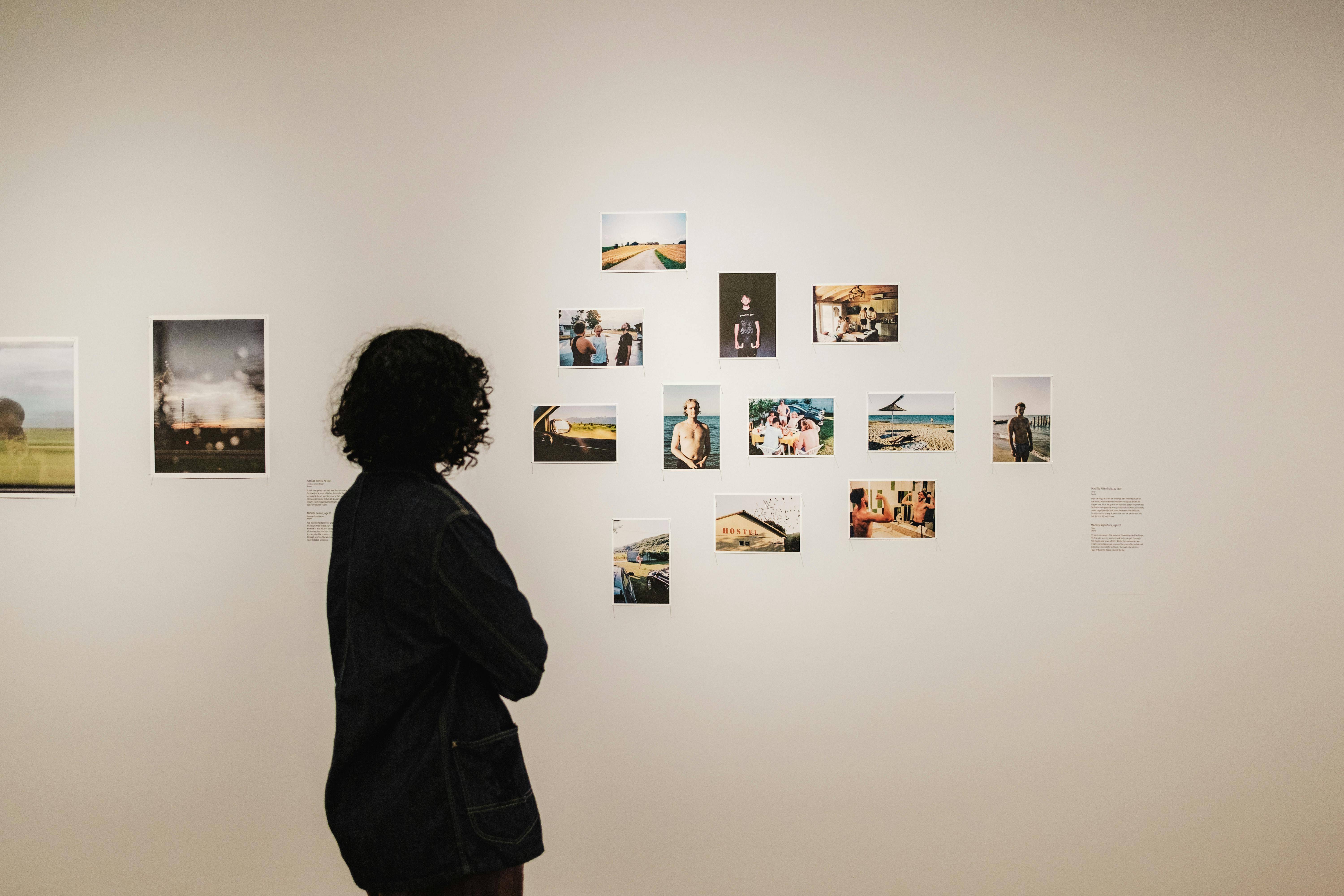 Woman stands in front of an art gallery in Coronado with small photographs on the wall