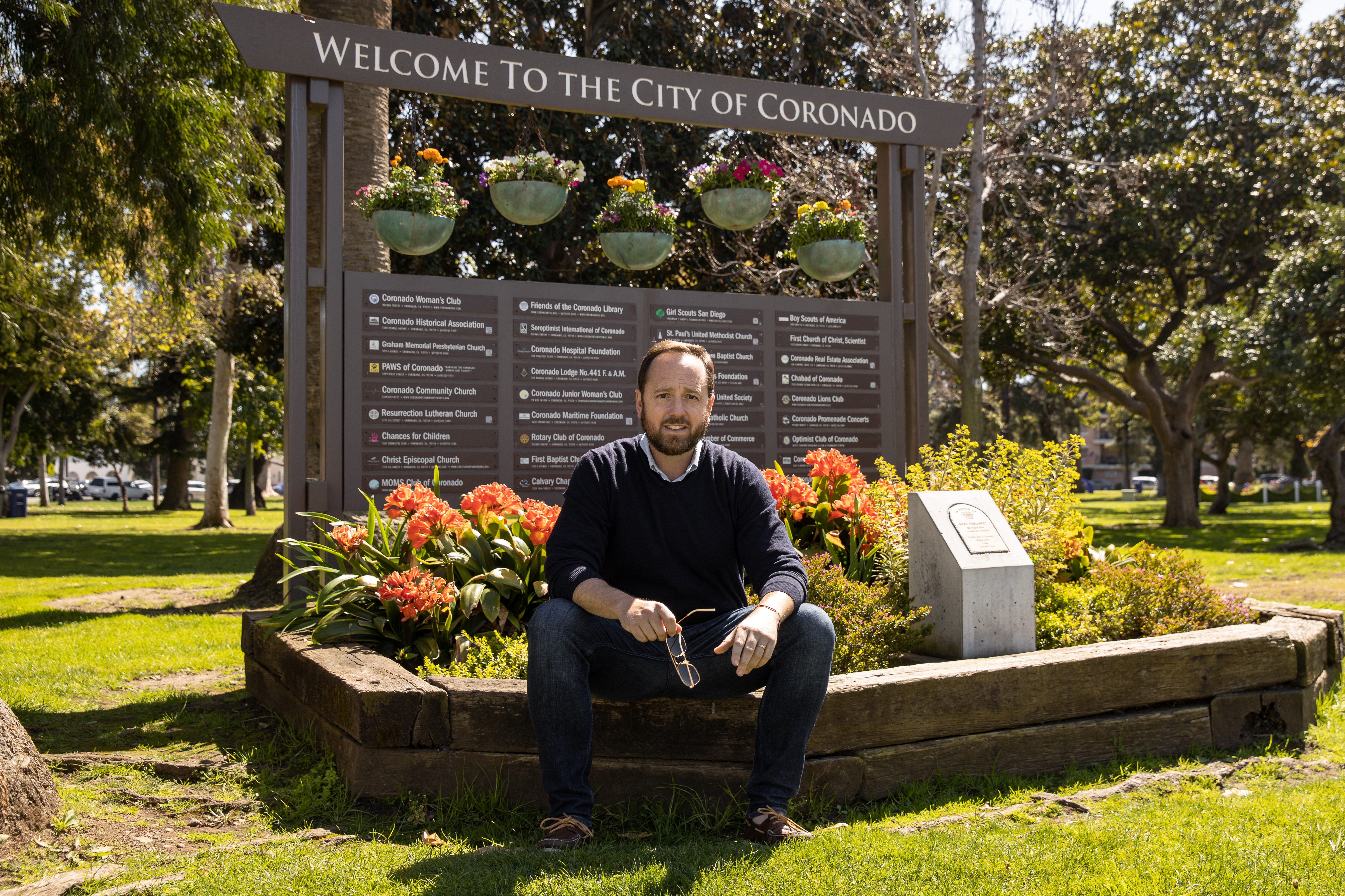 Top Coronado real estate agent and best local realtor Whitney Benzian sits beside the city of Coronado welcome sign