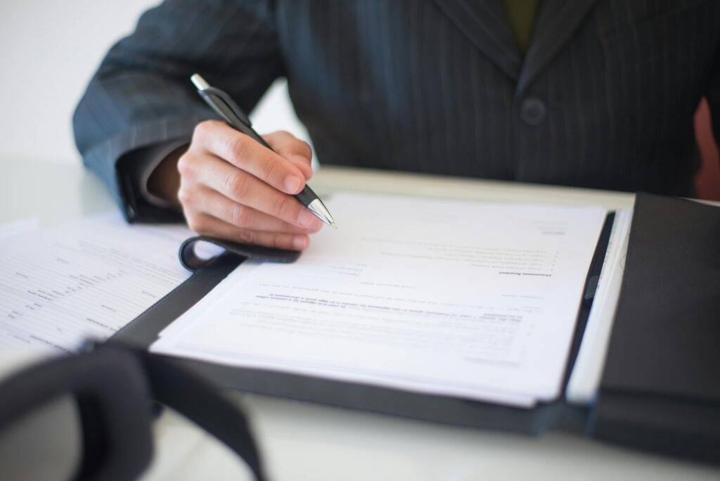 Person signing a contract legal document such as a Coronado probate agreement to put your home in a trust with support from the best local realtor agent Whitney Benzian