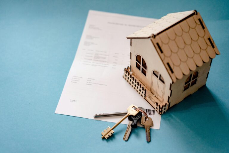 Wooden toy house on mortgage papers and keys, representing financing a home purchase in Coronado for buyers and sellers of real estate
